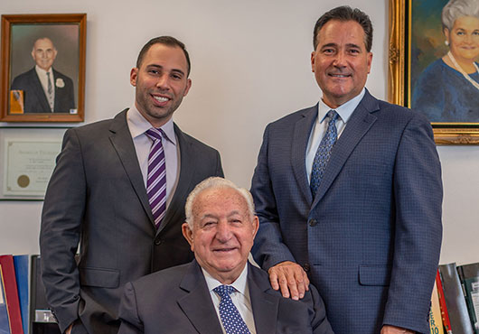 Salvatore Strocchia, Vice President of Operations (left), CEO Edward Strocchia (seated) and President Philip Strocchia are the family team that leads EPS Iron Works Inc. In the background are portraits of others in the Strocchia family.